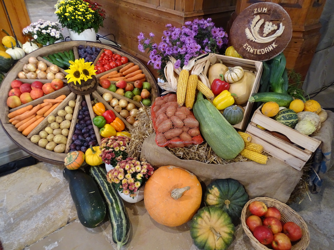 Erntedank-Schmuck Obst Brot und Gemuese in einem Wagenrad Koerben