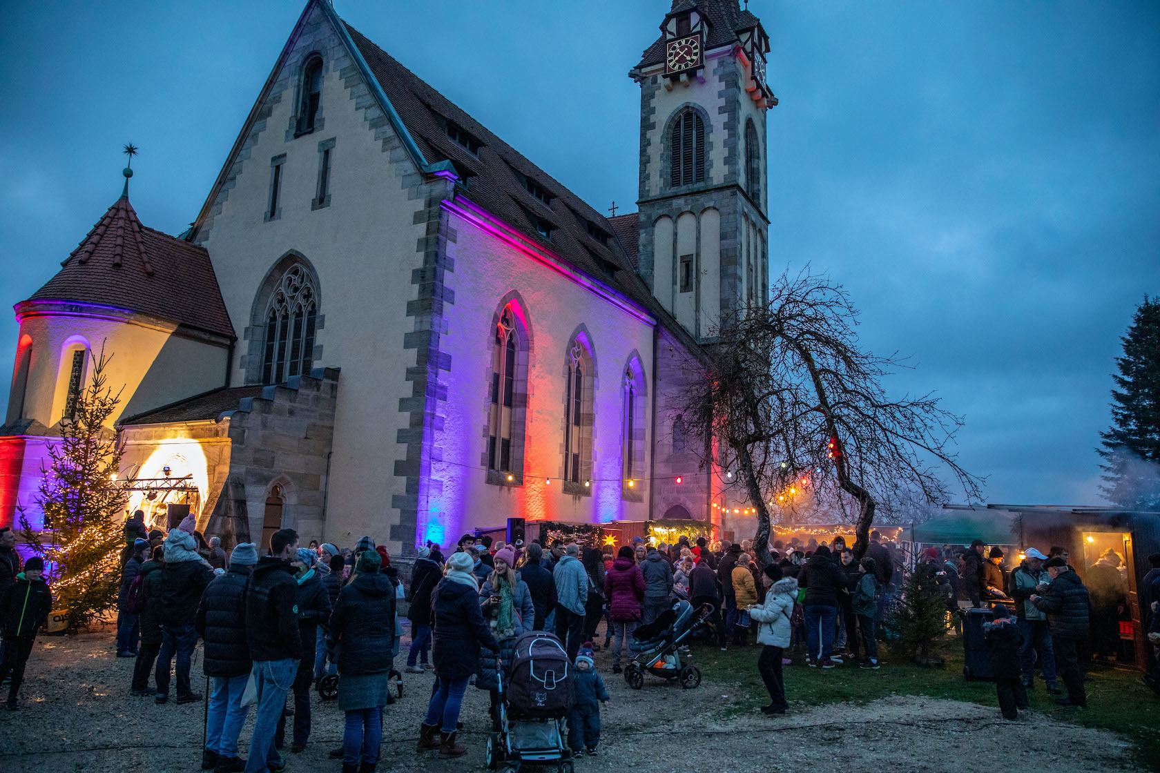 Glockenmarkt am Abend mit Besuchern und Kirche im Hintergrund