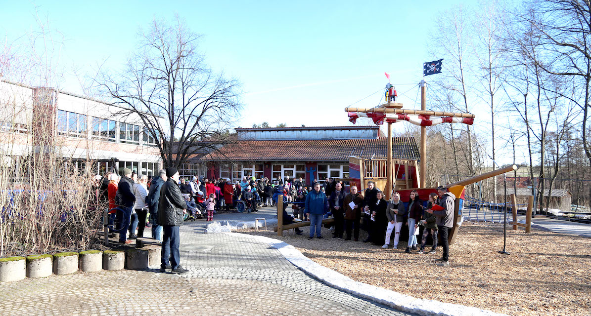 Gruppe im Schulhof vor Piratenschiff auf Spielplatz